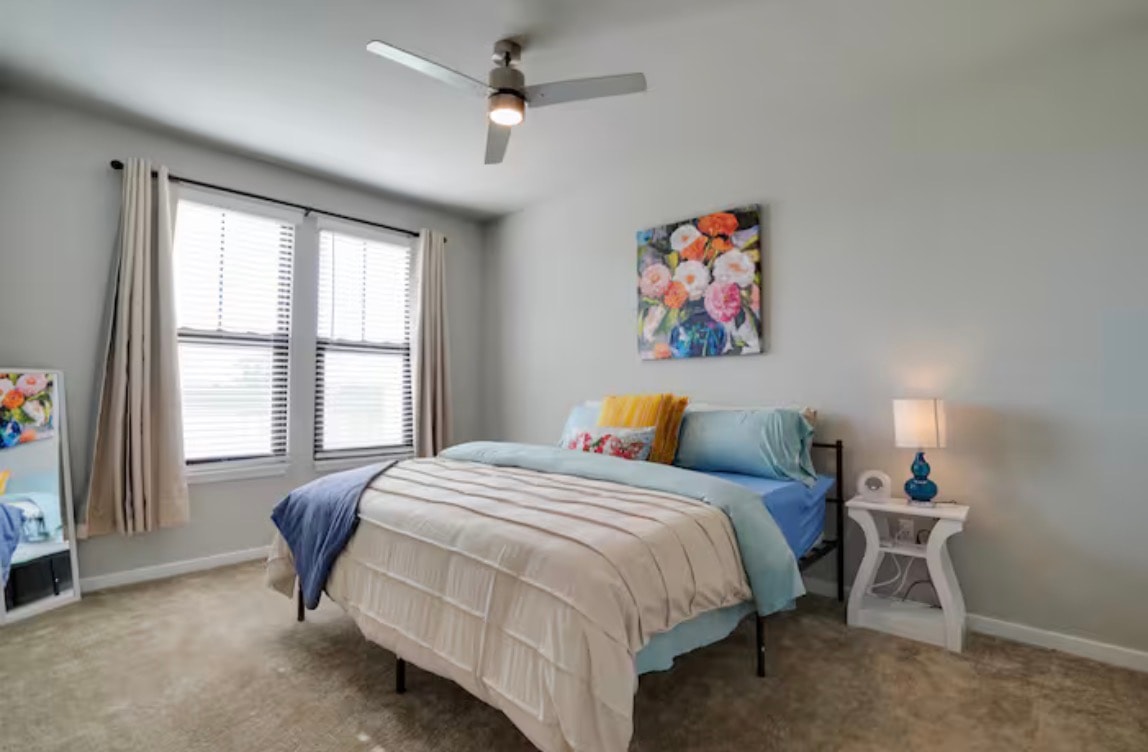 Bright bedroom with floral artwork and ceiling fan